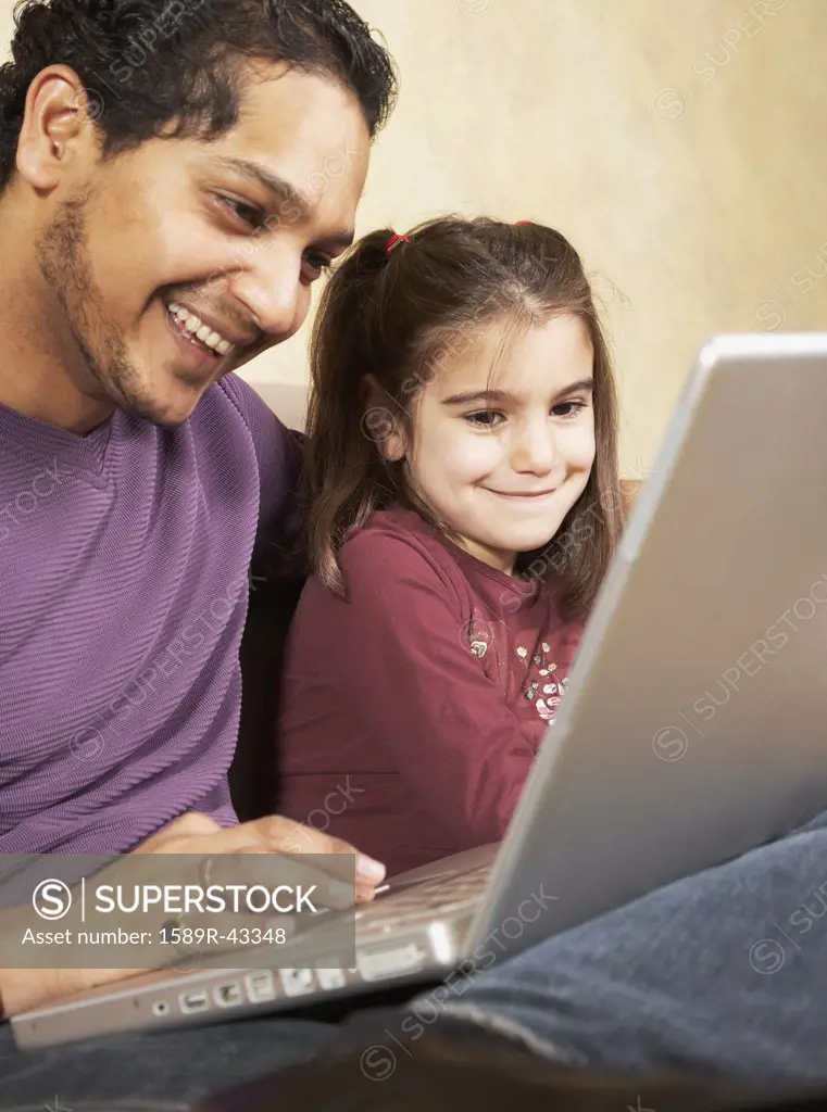 Indian father and daughter looking at laptop