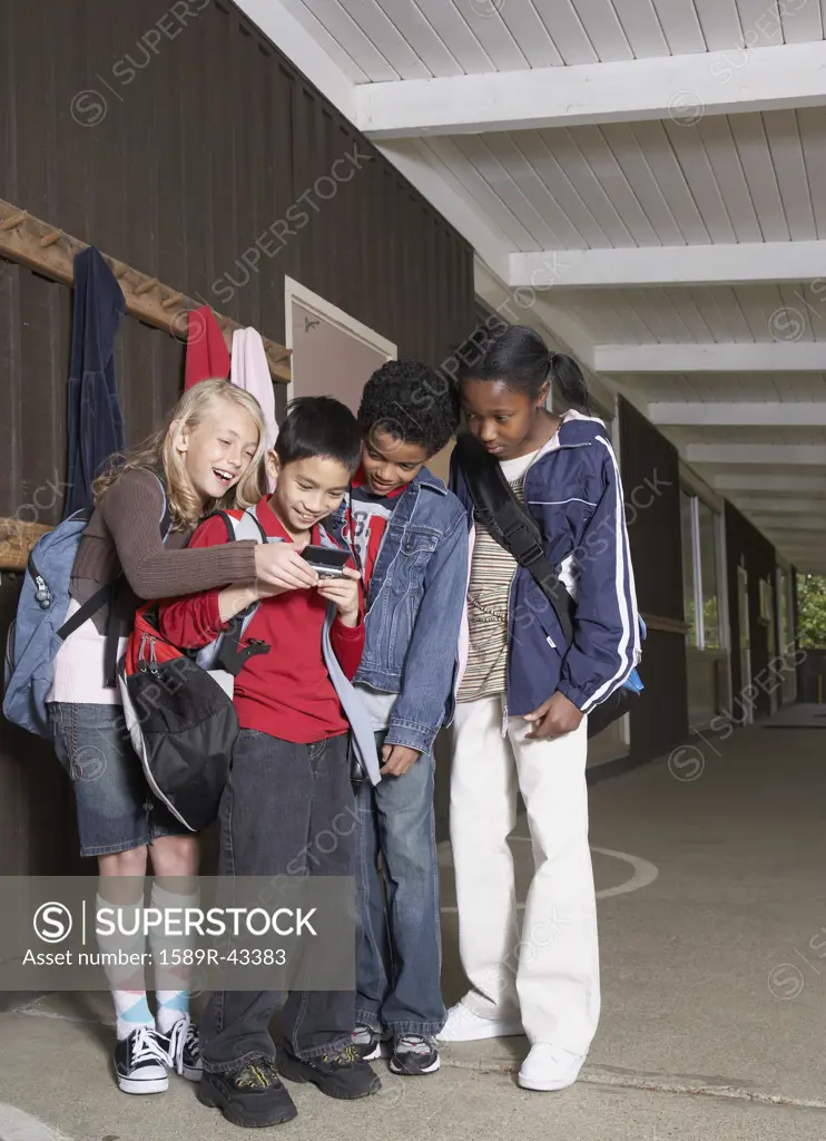 Multi-ethnic school children looking at cell phone
