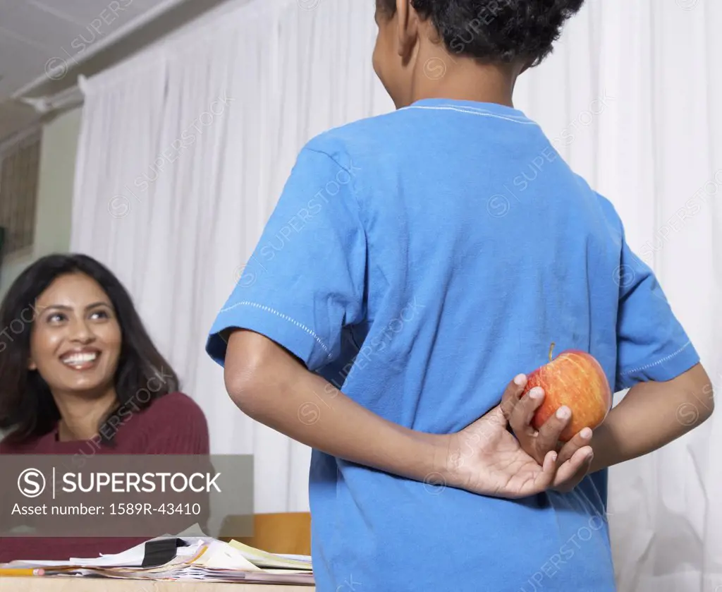 Mixed Race boy giving apple to teacher