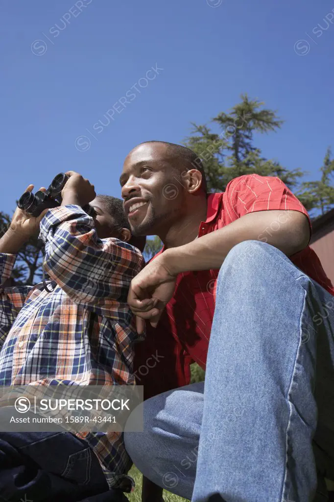 African father and son using binoculars