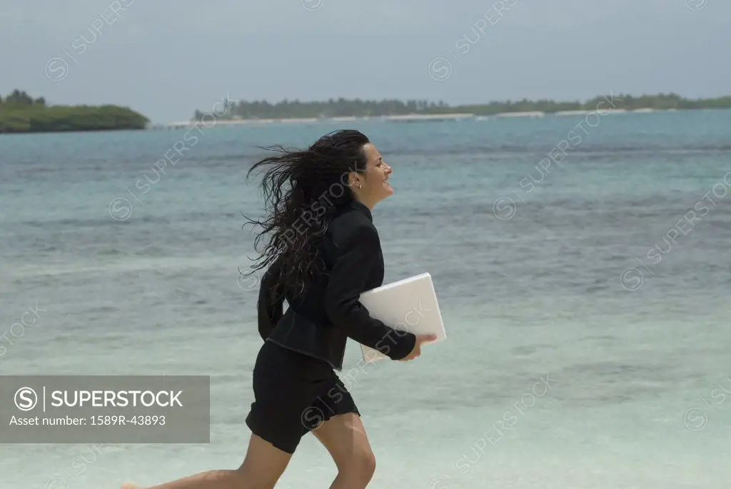Hispanic businesswoman running on beach