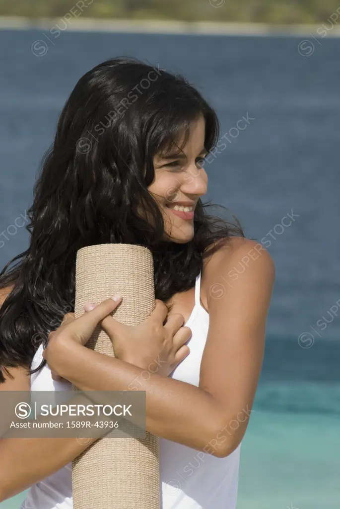 Hispanic woman holding beach mat