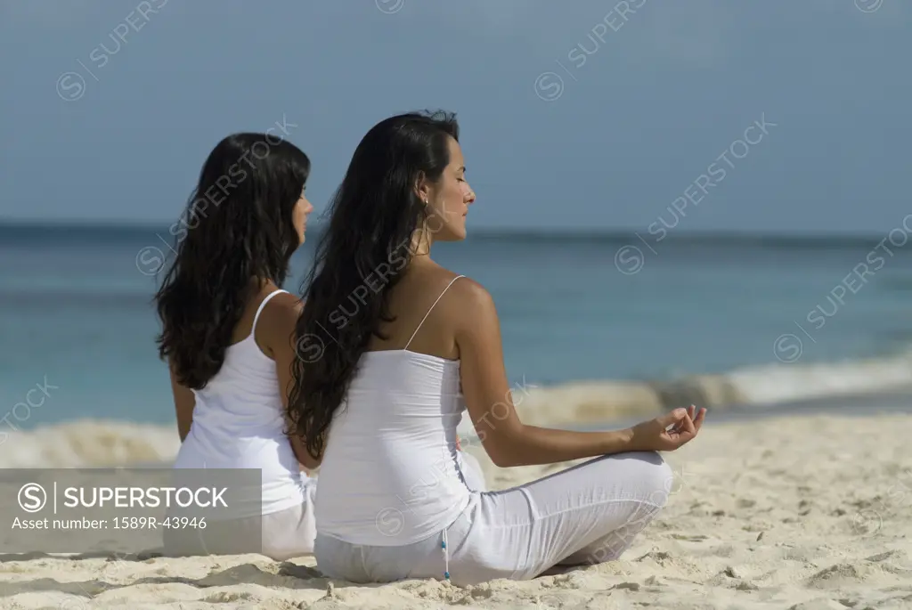Hispanic women meditating at beach