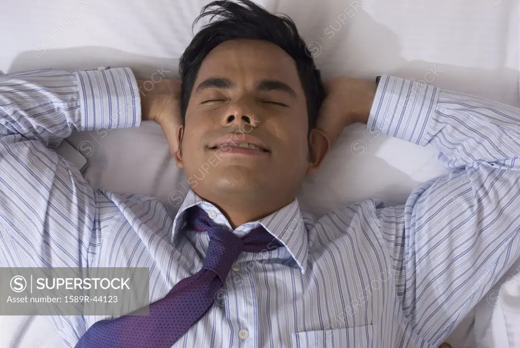 Hispanic businessman laying on bed