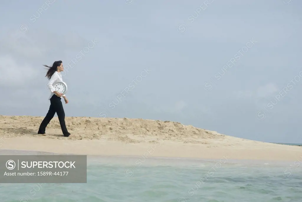 Woman carrying clock at beach