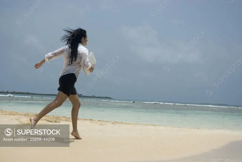 Hispanic woman running on beach
