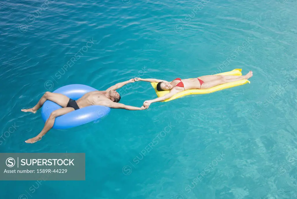 Multi-ethnic couple on floats in water