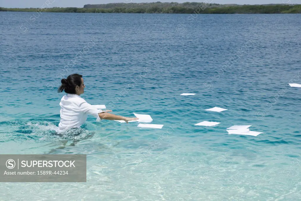 Hispanic businesswoman in water with paperwork