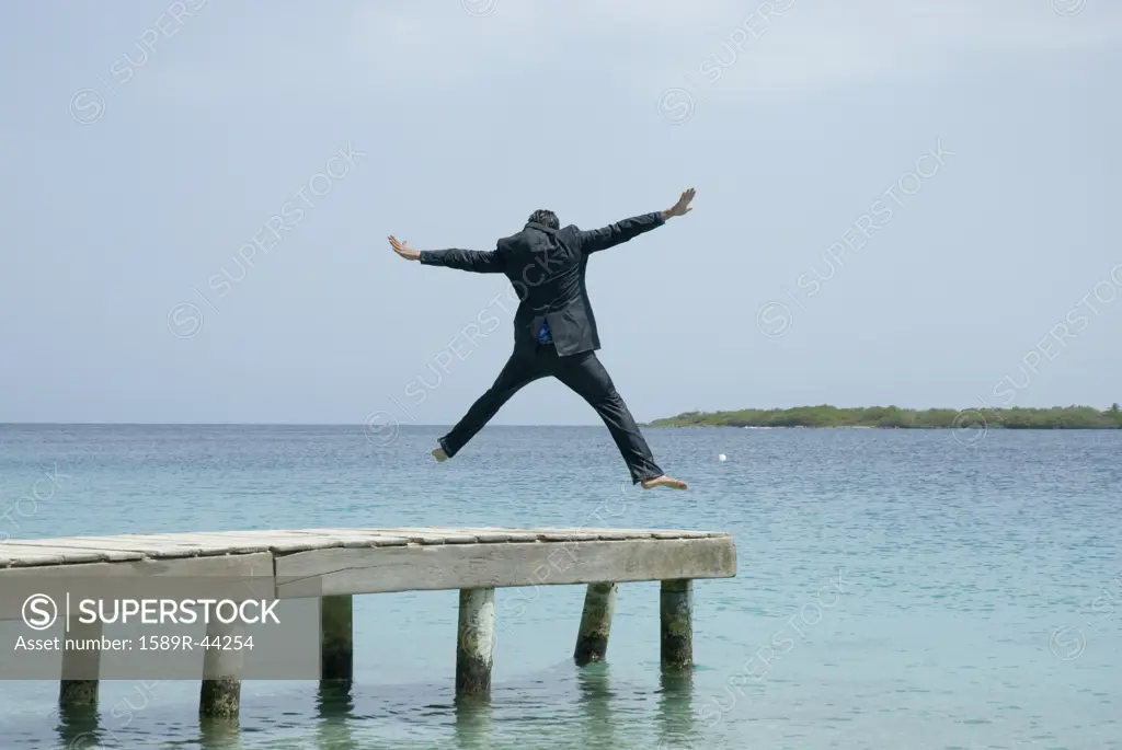 Hispanic businessman jumping on dock