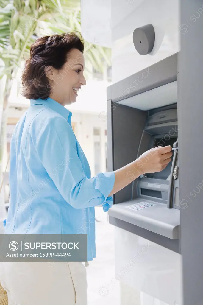 Hispanic woman using automatic teller machine