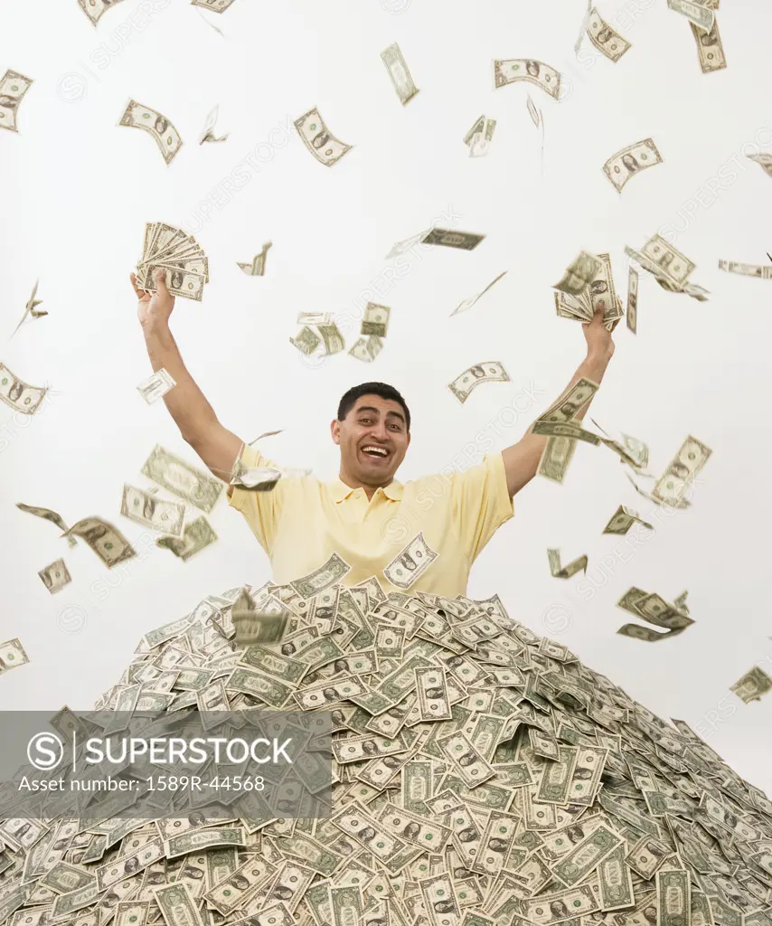 Hispanic man standing in pile of money