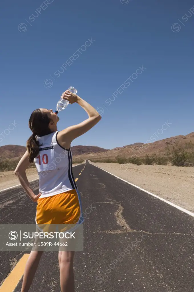 Mixed Race female runner drinking water
