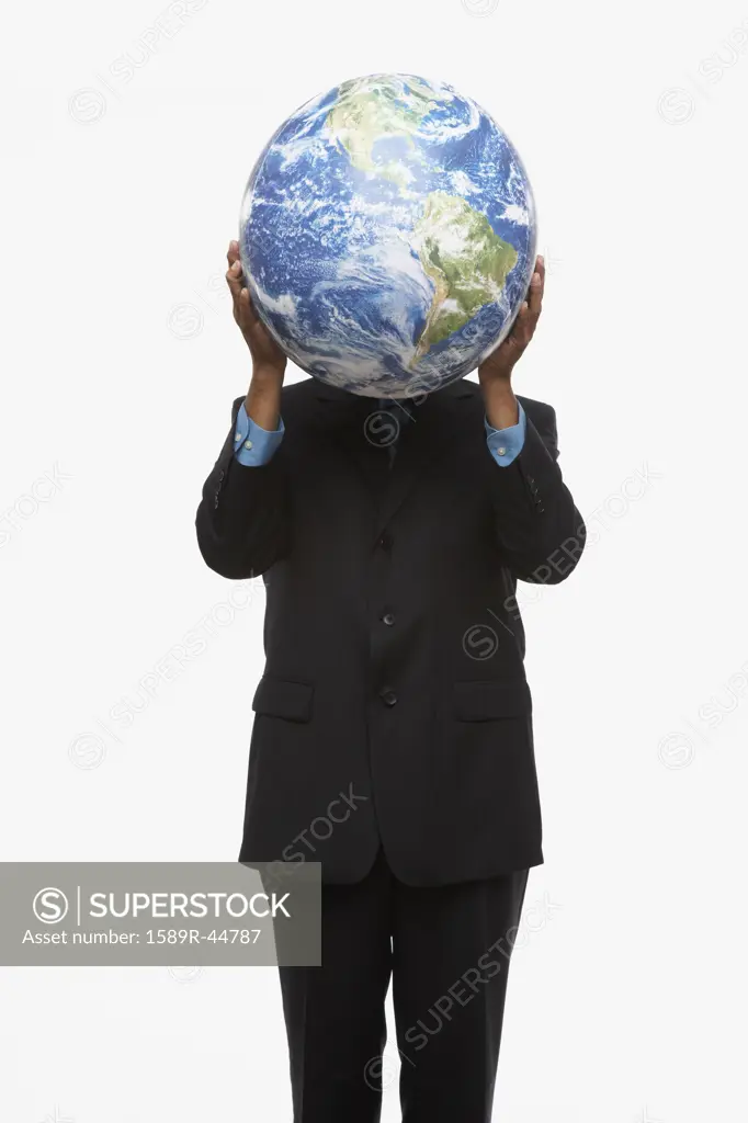 Hispanic businessman holding globe over face