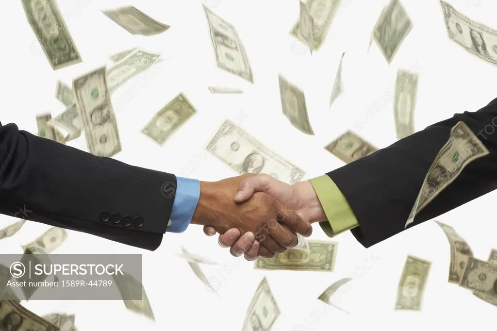 Businesspeople shaking hands in rain of money