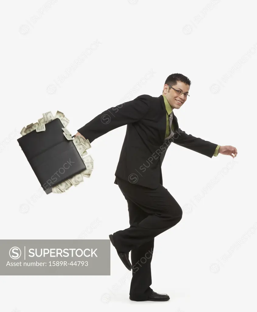 Hispanic businessman holding briefcase full of money