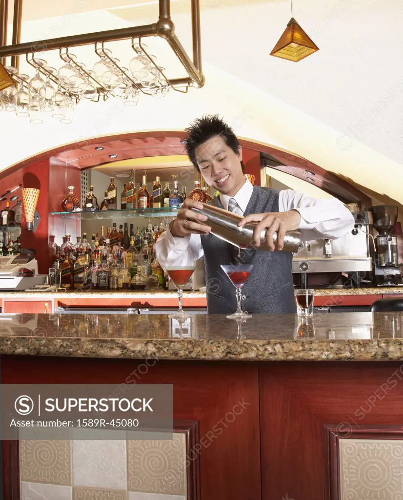 Asian male bartender pouring cocktails