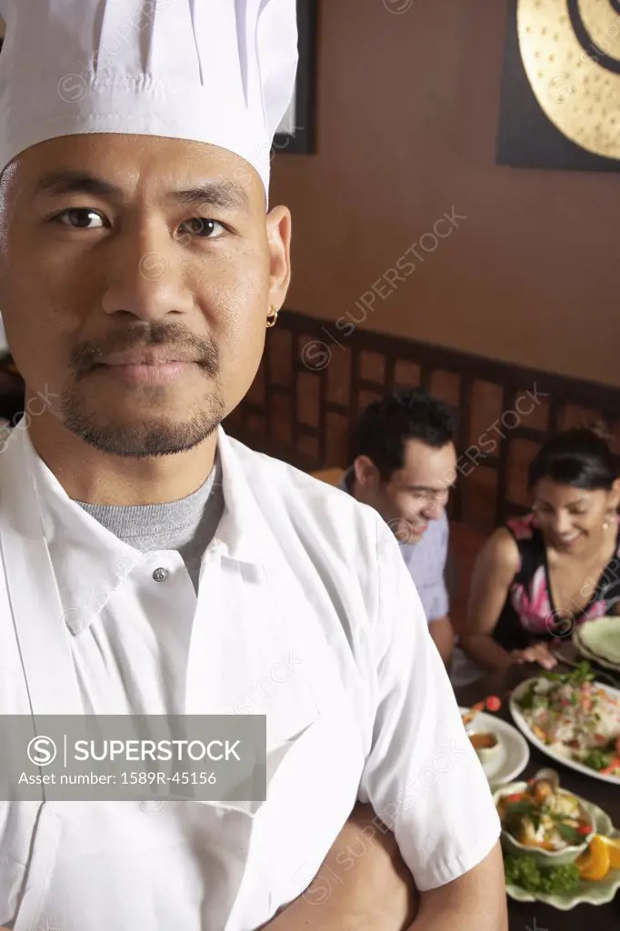 Asian male chef with diners in background