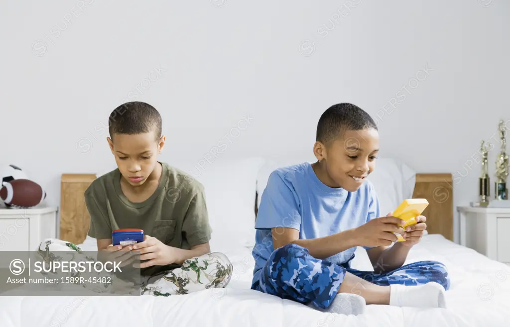 African American brothers playing handheld video games