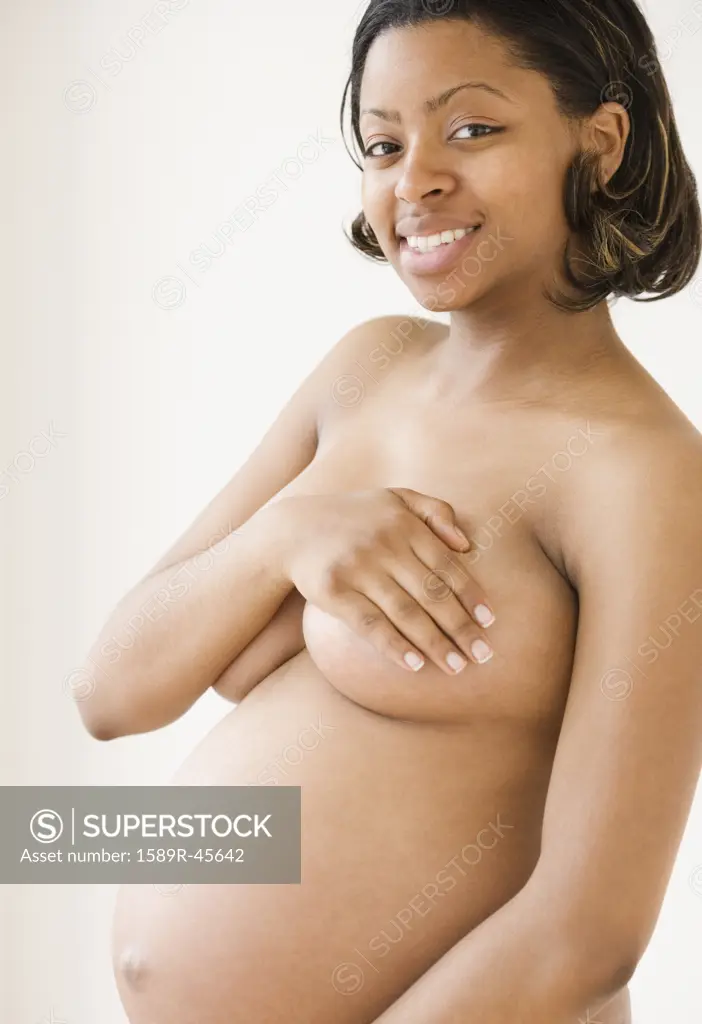 Nude pregnant African American woman covering breasts