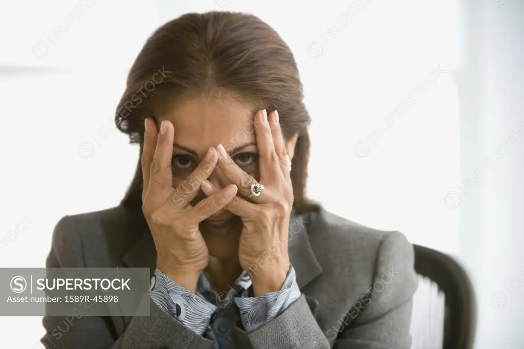 Hispanic businesswoman peeking through fingers