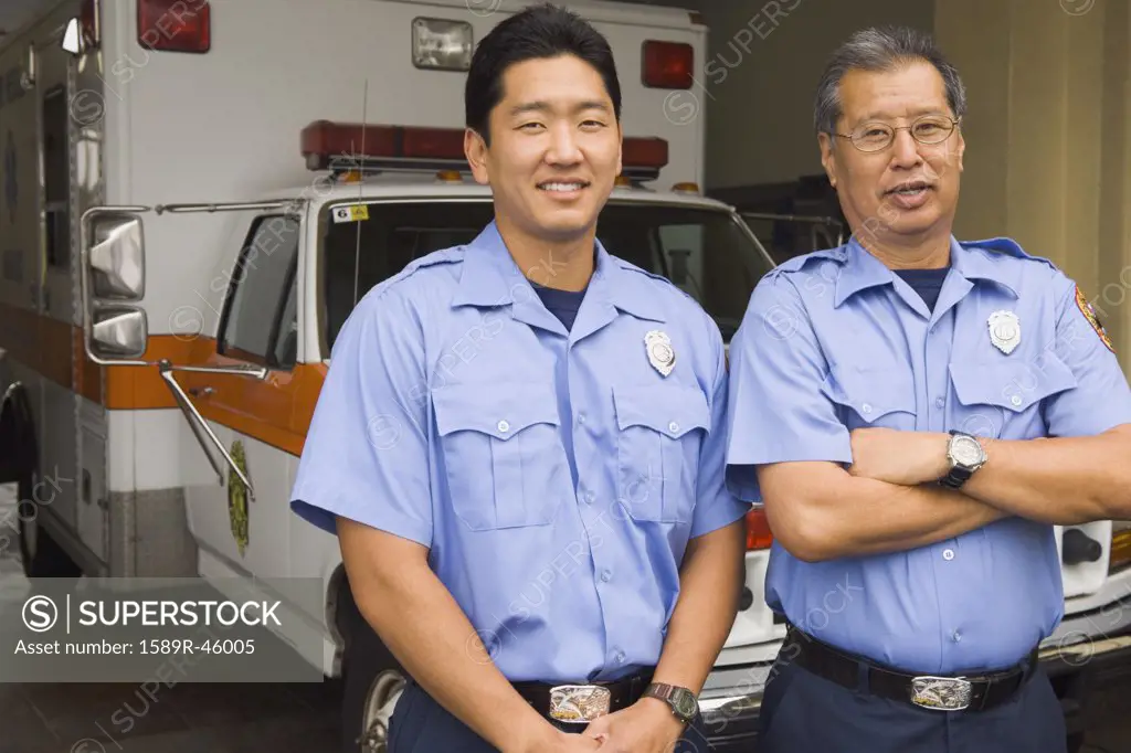 Asian male paramedics in front of ambulance