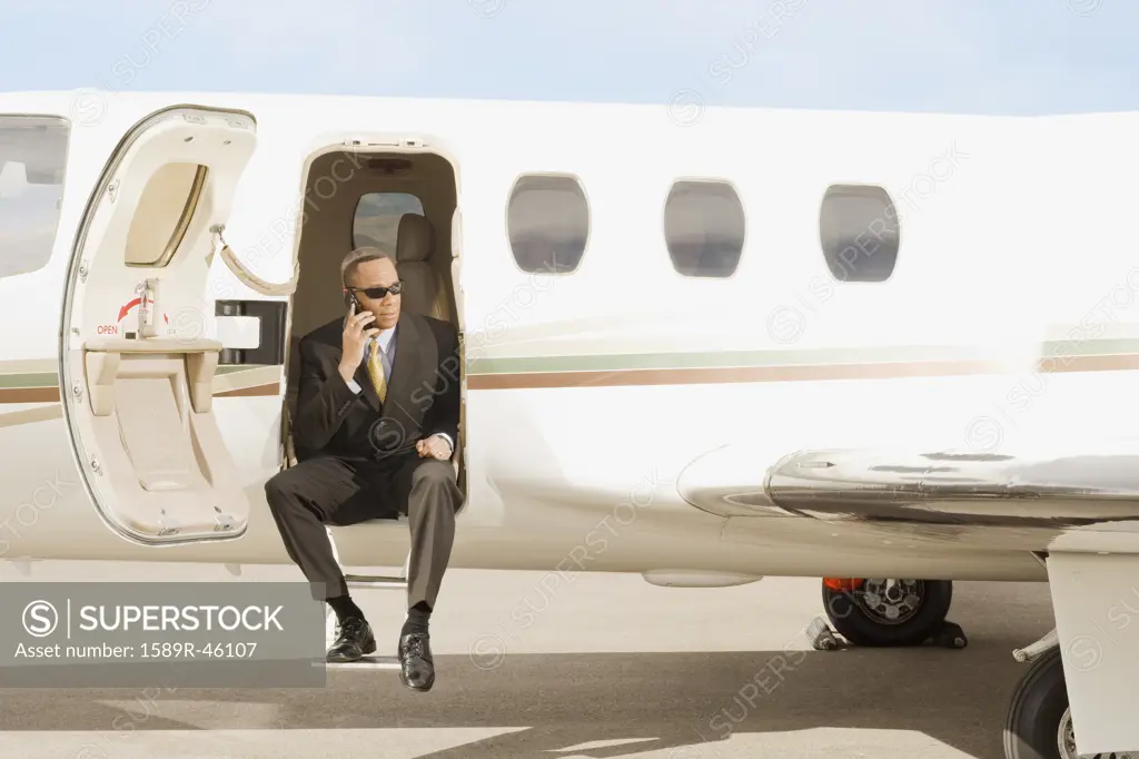 African American businessman sitting in airplane doorway