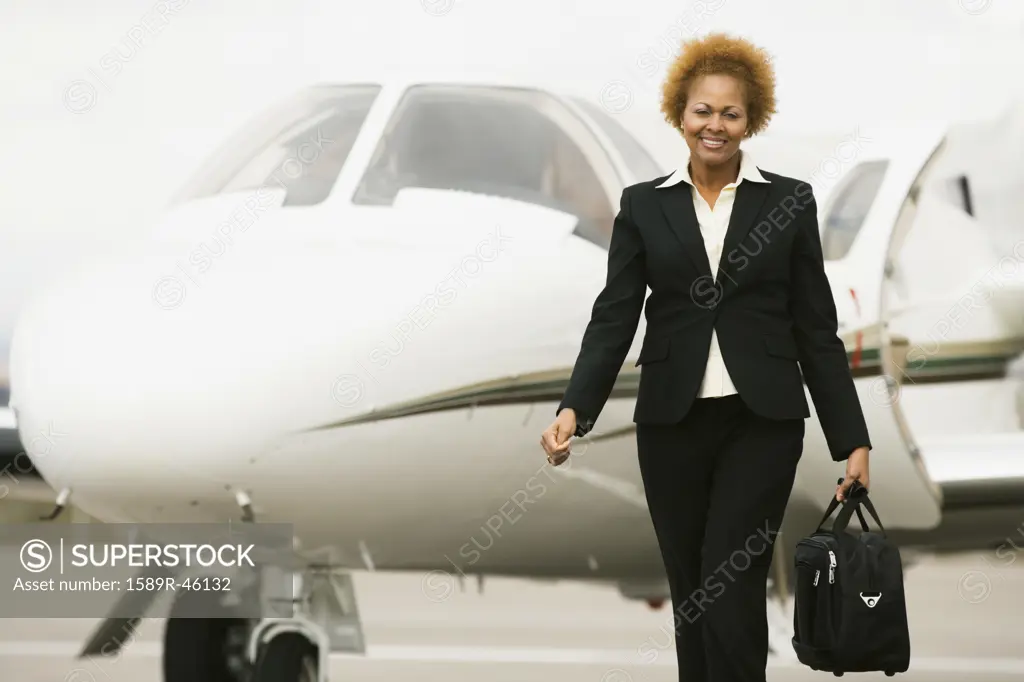 African American businesswoman walking away from airplane