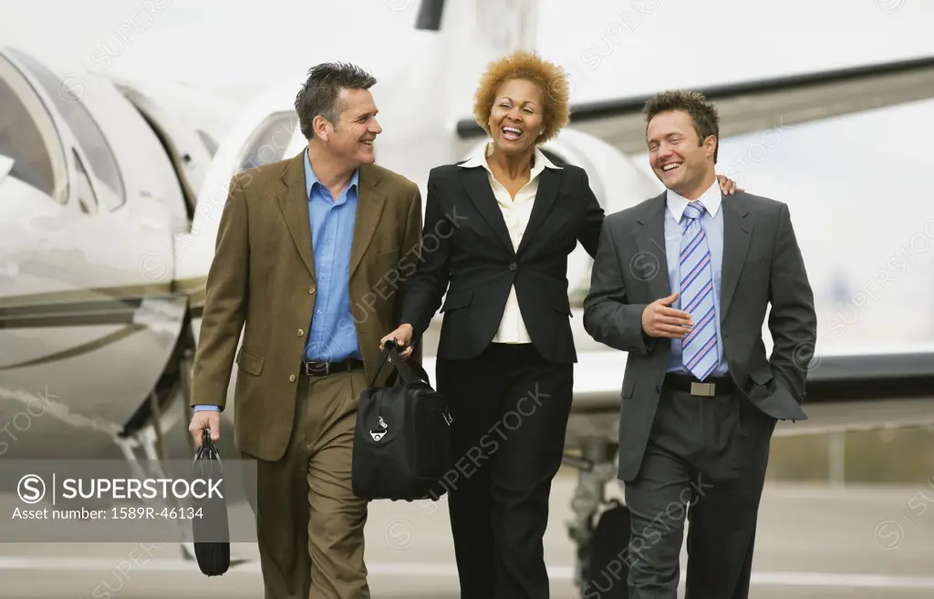 Multi-ethnic businesspeople walking away from airplane