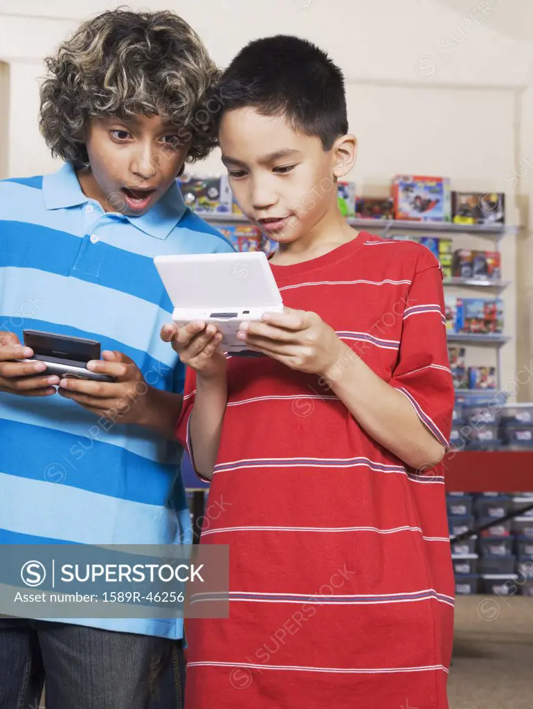 Multi-ethnic boys playing handheld video games