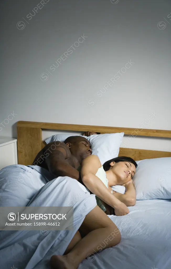 Multi-ethnic couple sleeping in bed