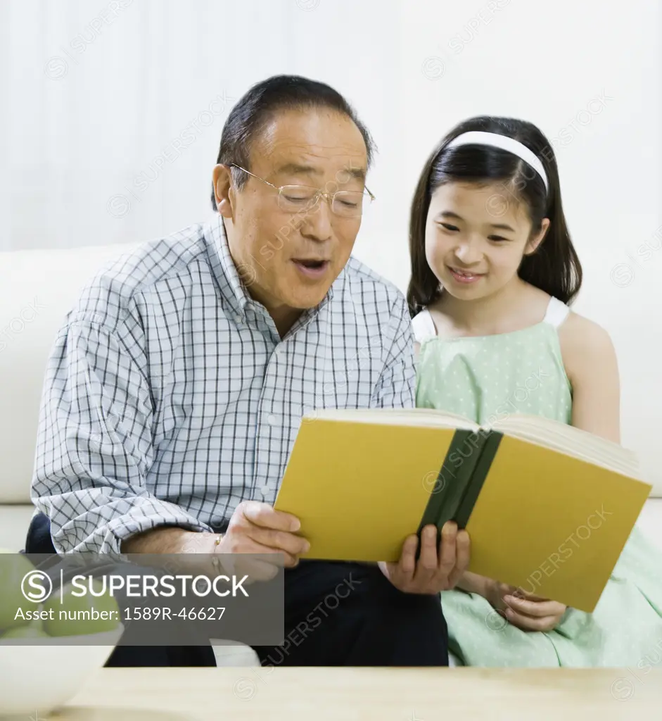 Asian grandfather reading to granddaughter