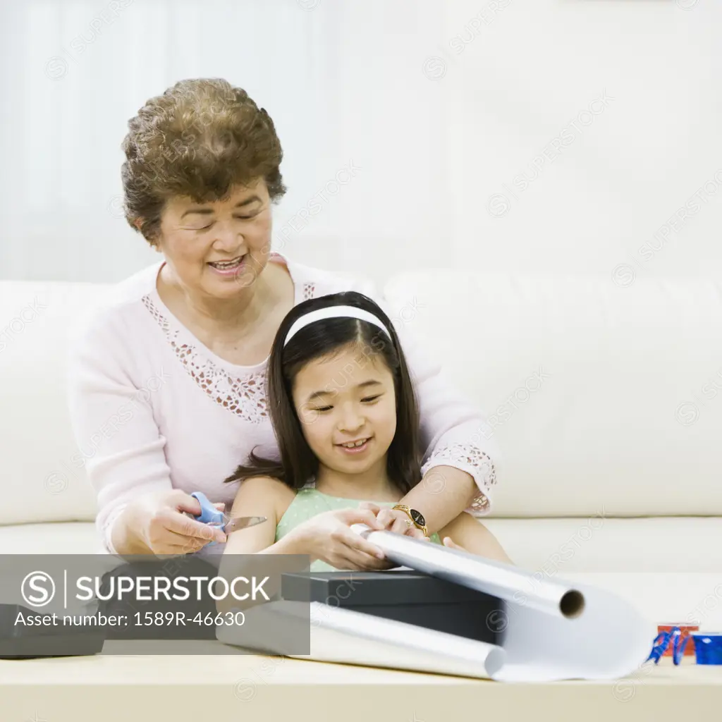 Asian grandmother and granddaughter wrapping gift