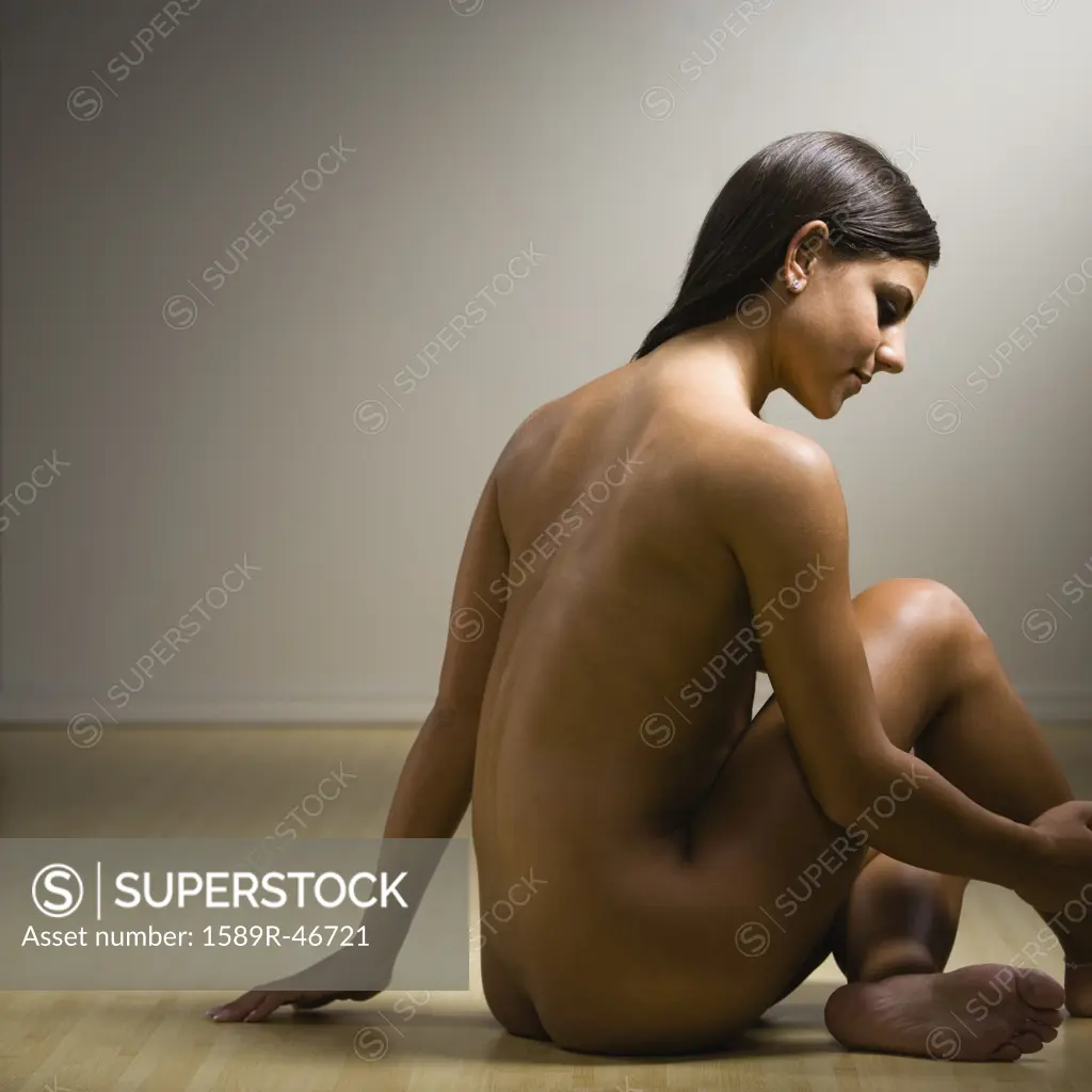 Nude woman sitting on floor