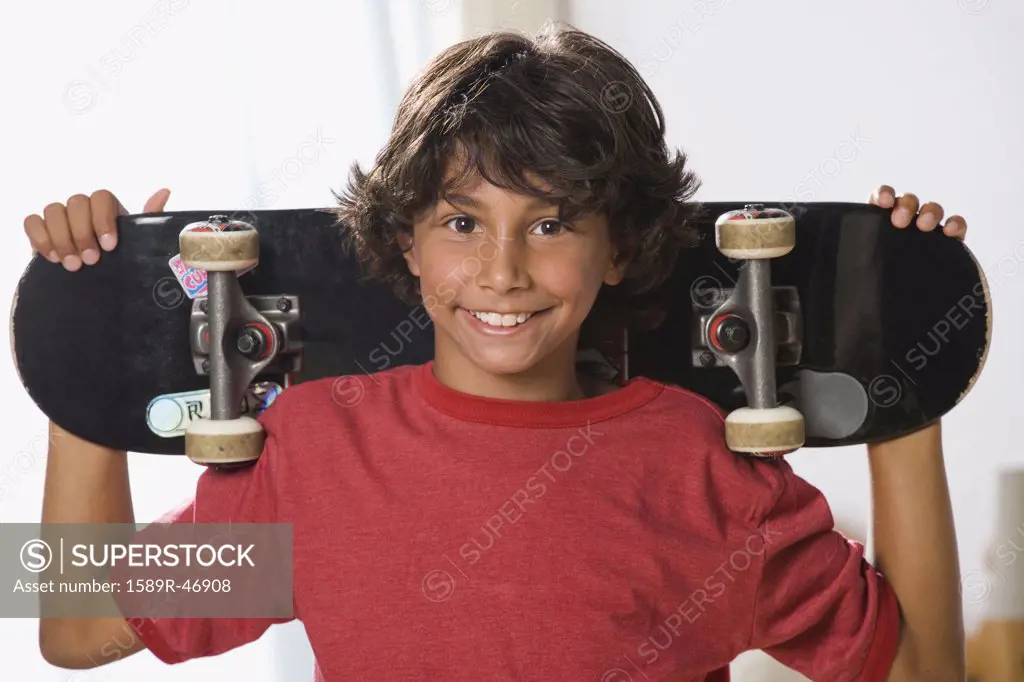 Mixed Race boy holding skateboard