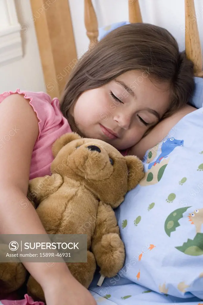 Hispanic girl sleeping with teddy bear