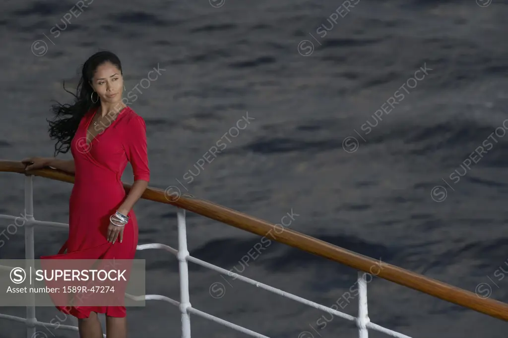 Hispanic woman leaning on ship railing