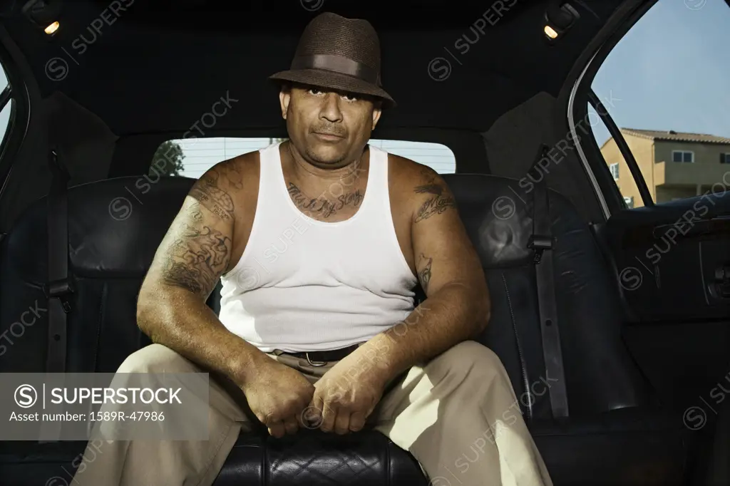 Tattooed Hispanic man in limousine