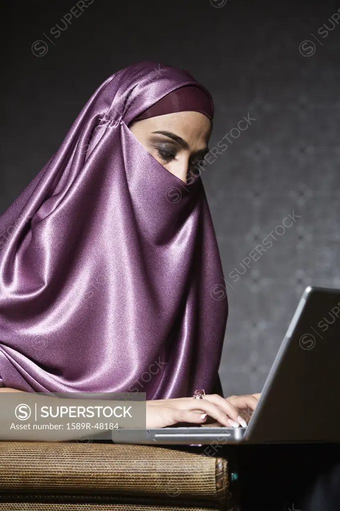 Middle Eastern woman typing on laptop