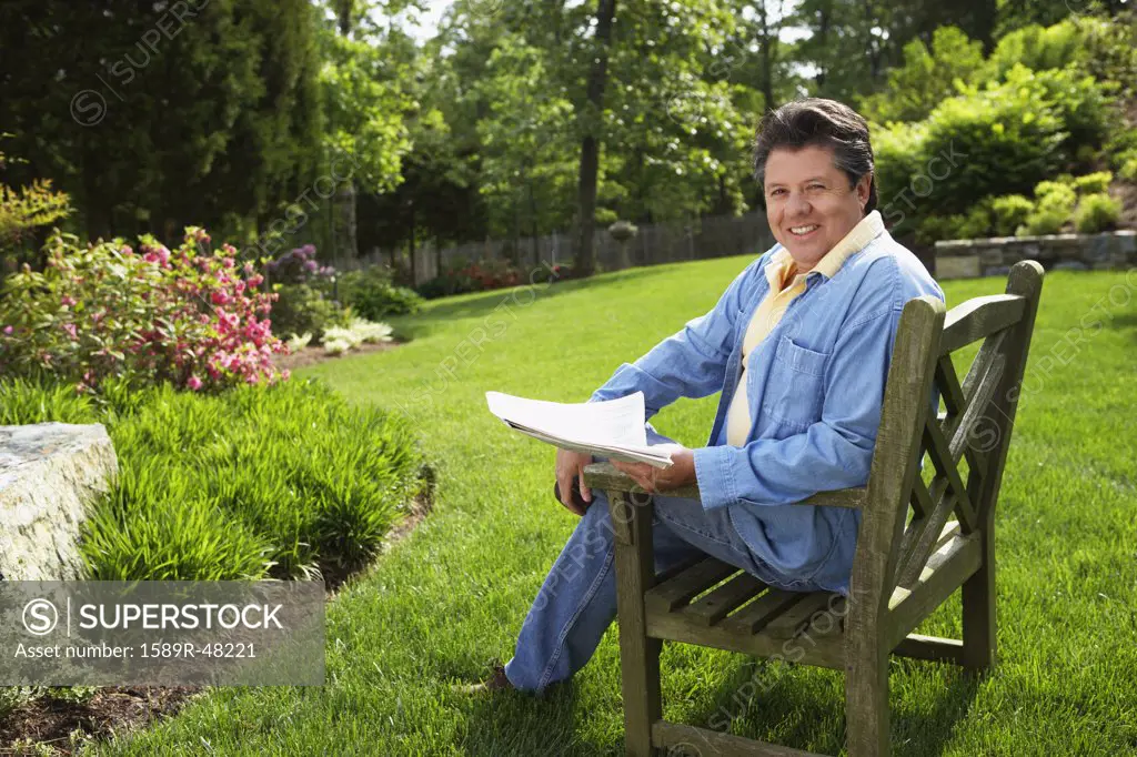 Hispanic man reading in backyard