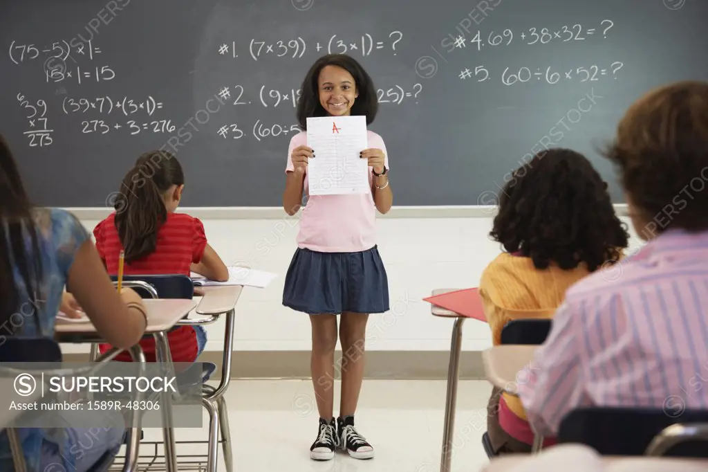 African American girl holding paper in front of class