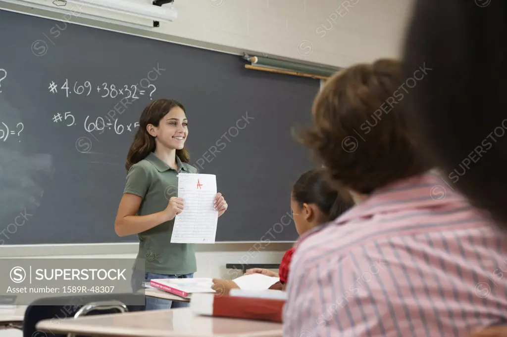 Girl holding paper in front of class