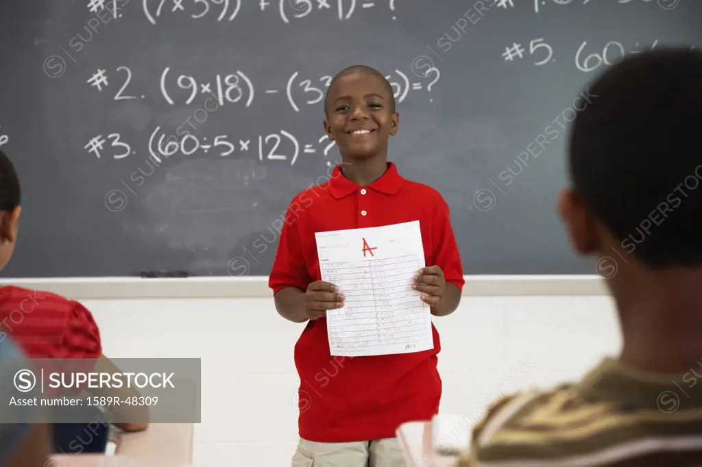 African American boy holding paper in front of class