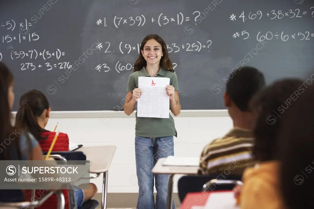 Girl holding up paper in front of class