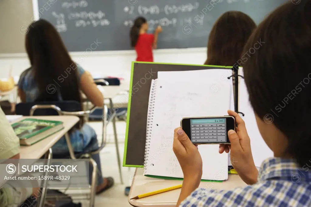 Asian boy using calculator in class