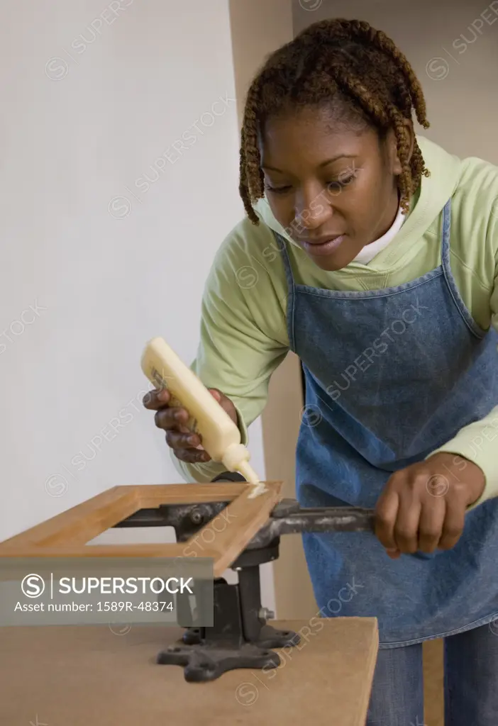 African American woman gluing piece of wood