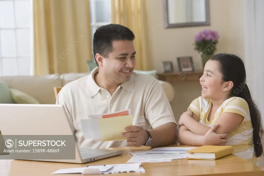 Hispanic father and daughter smiling at each other