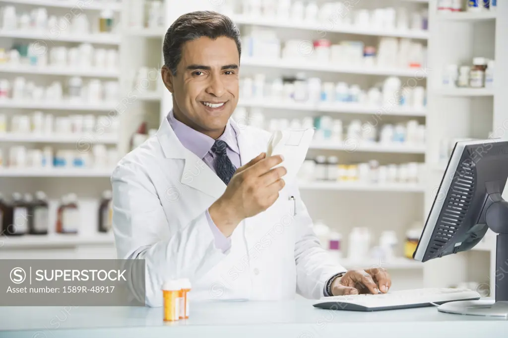 Hispanic male pharmacist holding prescription