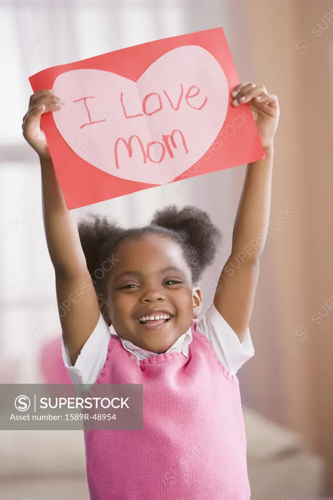 African American girl holding up valentine for mother