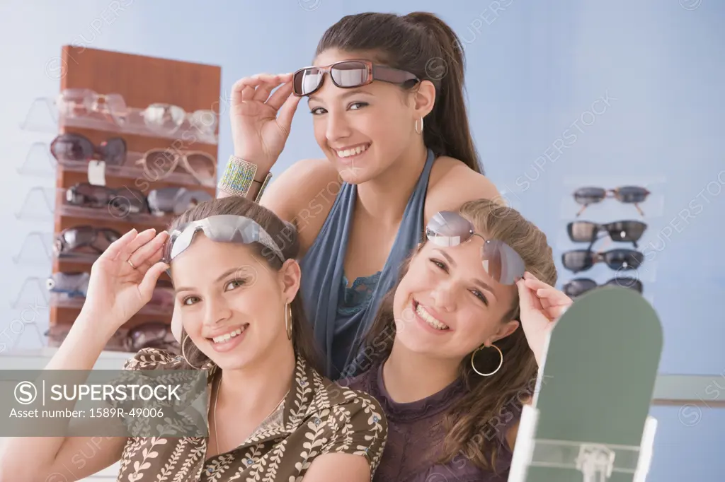 Multi-ethnic teenaged girls trying on sunglasses