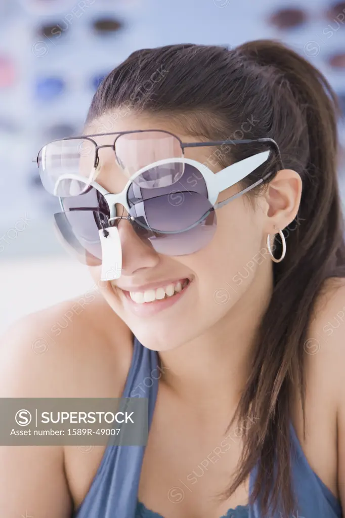 Hispanic teenaged girl trying on sunglasses